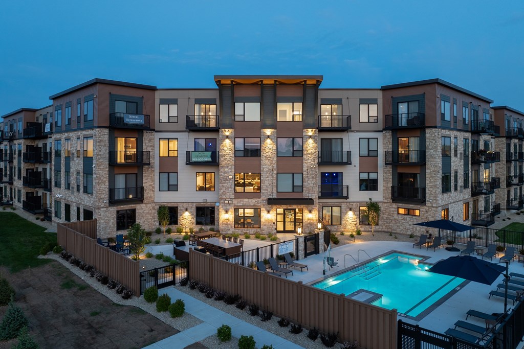 A modern apartment complex with a pool at dusk.