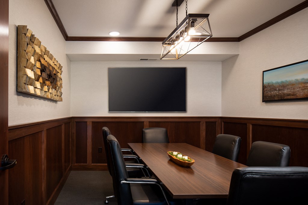 a conference room with a table and chairs and a tv on the wall  at Victoria Park and V2 Apartments, St. Paul, 55102