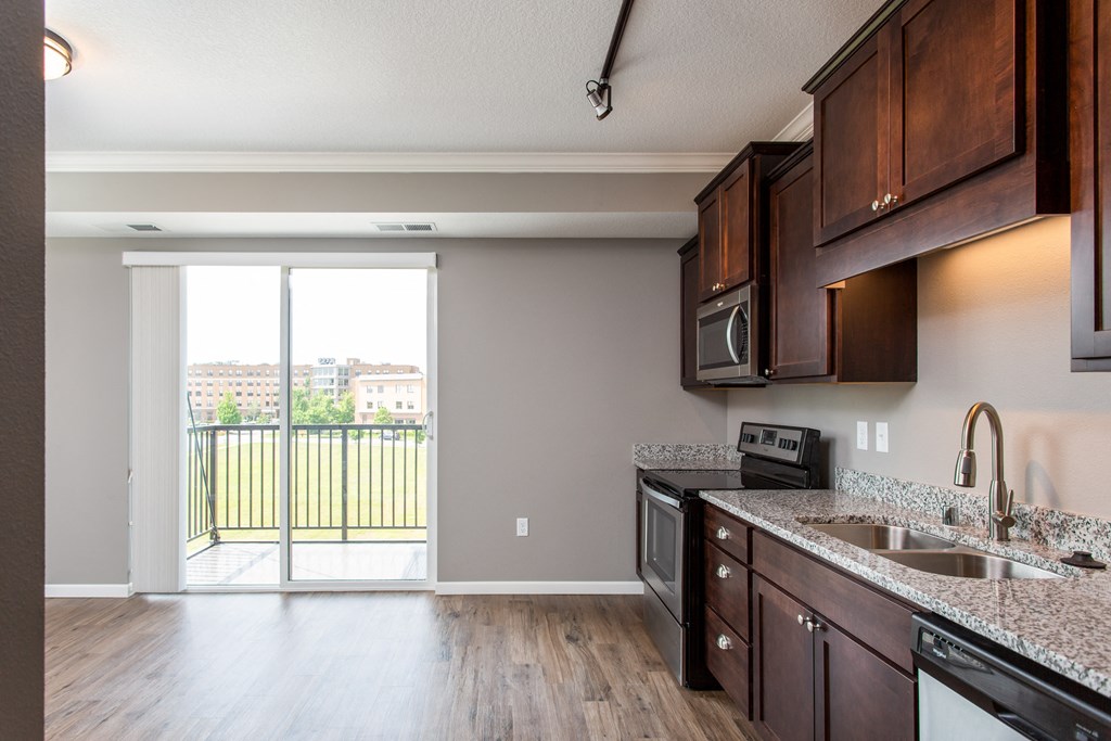 a kitchen with wood floors and a sliding glass door leading to a balcony  at Victoria Park and V2 Apartments, St. Paul