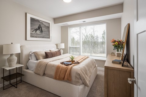 A bedroom with a bed, nightstand, and a painting on the wall.