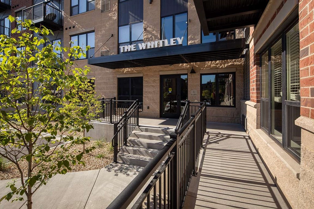 The Whitley building has a black railing and a tree in front of it.