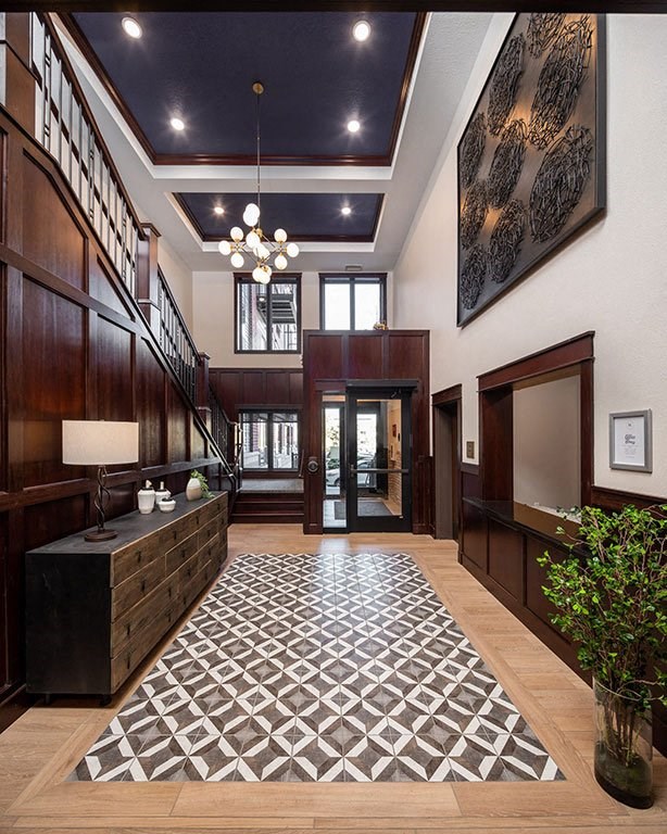 A hallway with a black and white tiled floor and a wooden staircase.