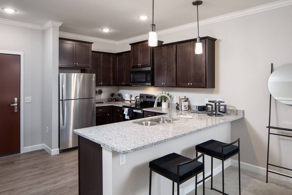 a kitchen with a large island with two stools in front of it at The Gallery Apartments, Burnsville, Minnesota