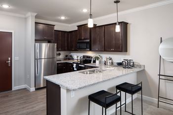 a kitchen with a large island with two stools in front of itat The Carver Apartments, Minnesota, 55318