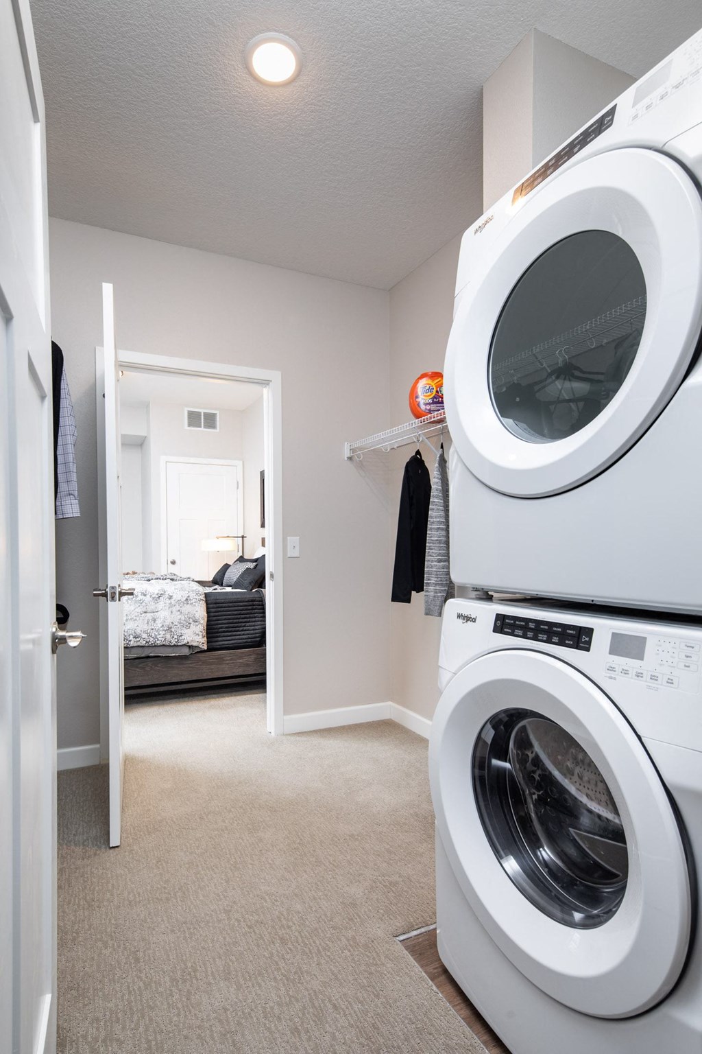 a washer and dryer in a laundry room with a connecting bedroom in the background at The Gallery Apartments, Burnsville, MN, 55337
