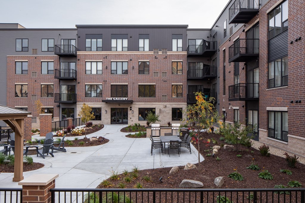 a courtyard with tables and chairs in front of an apartment building at The Gallery Apartments, Burnsville, MN, 55337