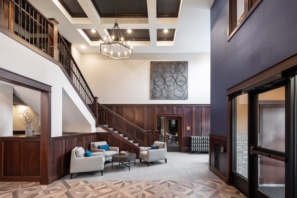 a large lobby with a staircase and chairs at The Gallery Apartments, Burnsville