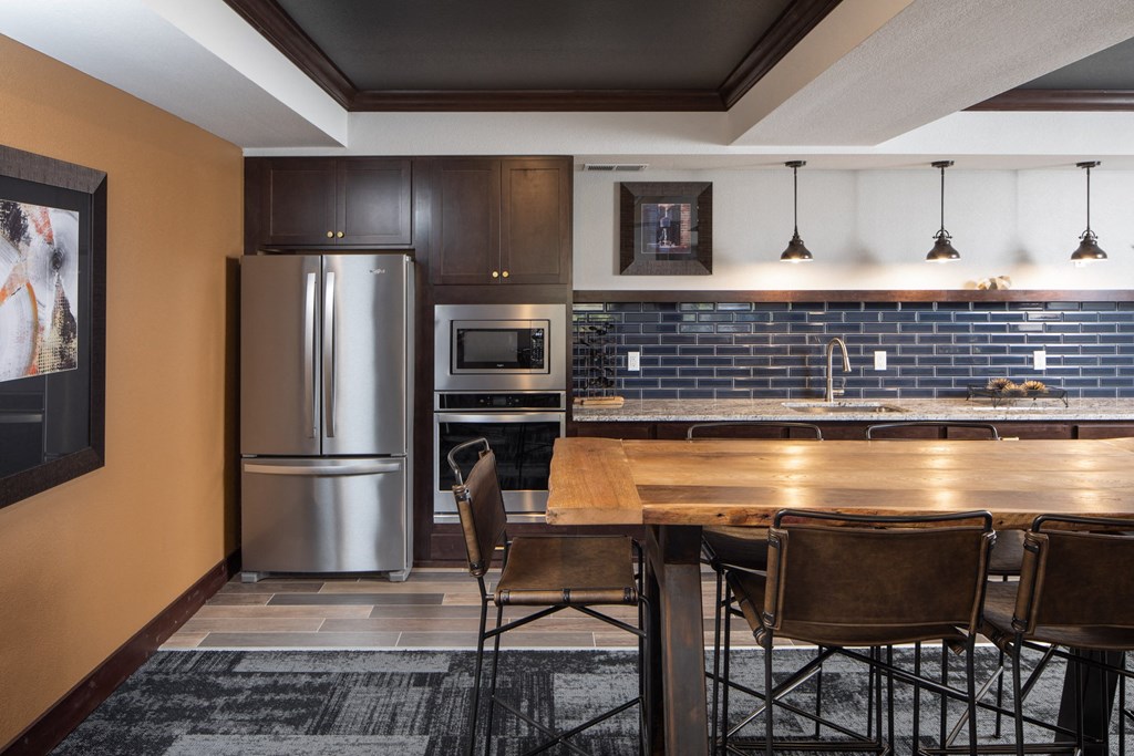 a community room with a kitchen with dark cabinets and a wooden table at The Gallery Apartments, Minnesota, 55337