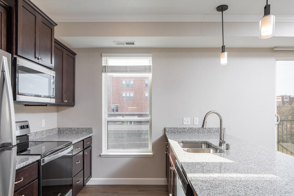 a kitchen with granite countertops and dark wood cabinets at The Gallery Apartments, Burnsville, MN