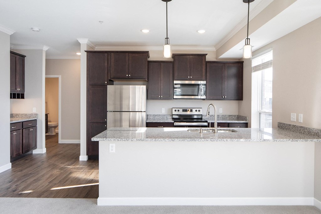a kitchen with dark wood cabinets and a granite counter top at The Gallery Apartments, Burnsville