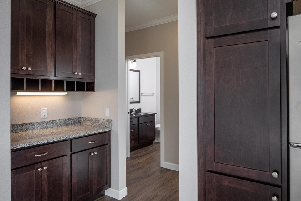 a kitchen with dark wood cabinets and granite countertops at The Gallery Apartments, Burnsville, Minnesota
