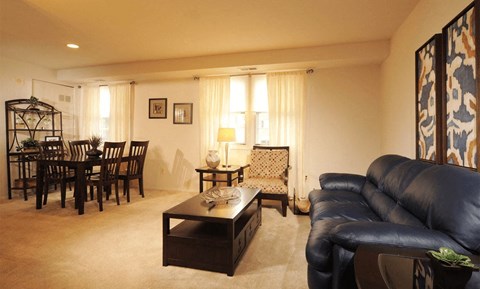 A living room with a black leather couch and a wooden coffee table.