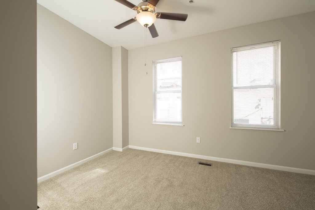 an empty living room with a ceiling fan and two windows at Queen Anne Belvedere, Baltimore