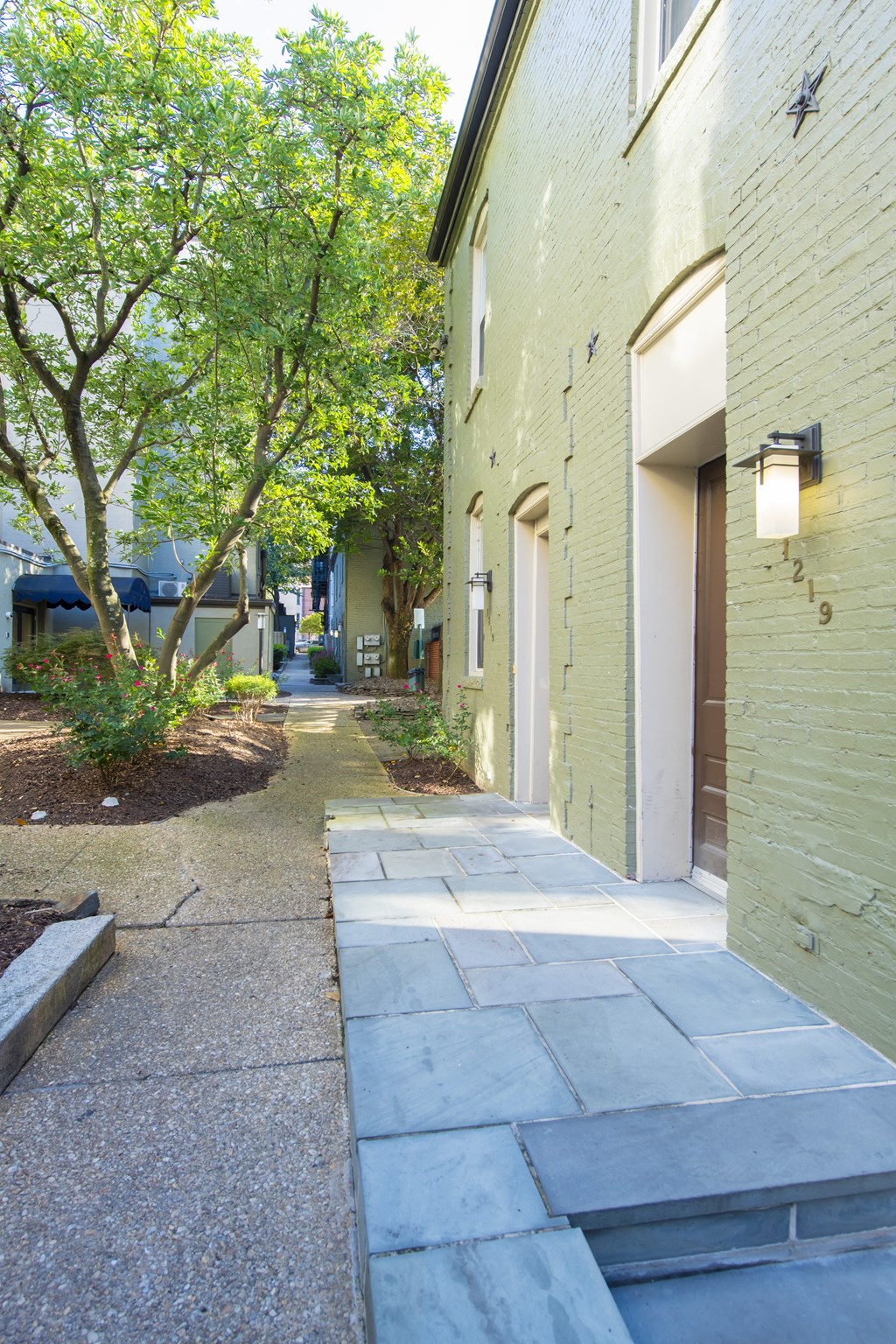 the sidewalk in front of the building is lined with trees at Queen Anne Belvedere, Baltimore, MD 21201