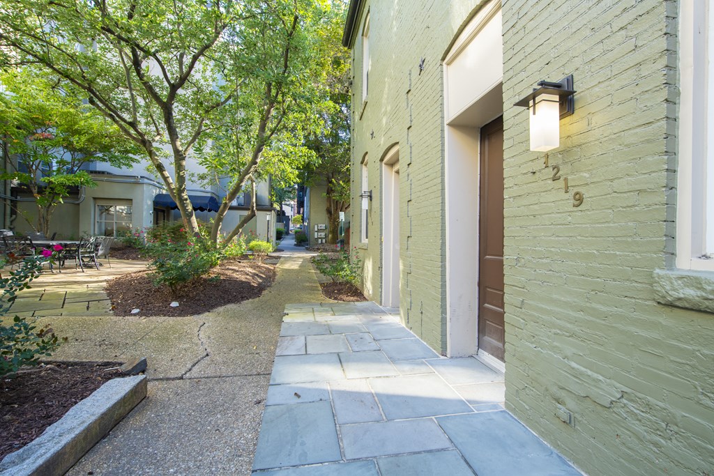 a walkway between two buildings with trees and plants at Queen Anne Belvedere, Baltimore, 21201
