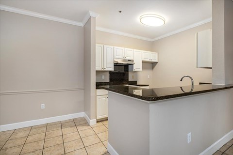 A kitchen with white cabinets and a black countertop.