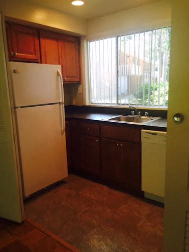 A kitchen with brown cabinets and a white refrigerator.