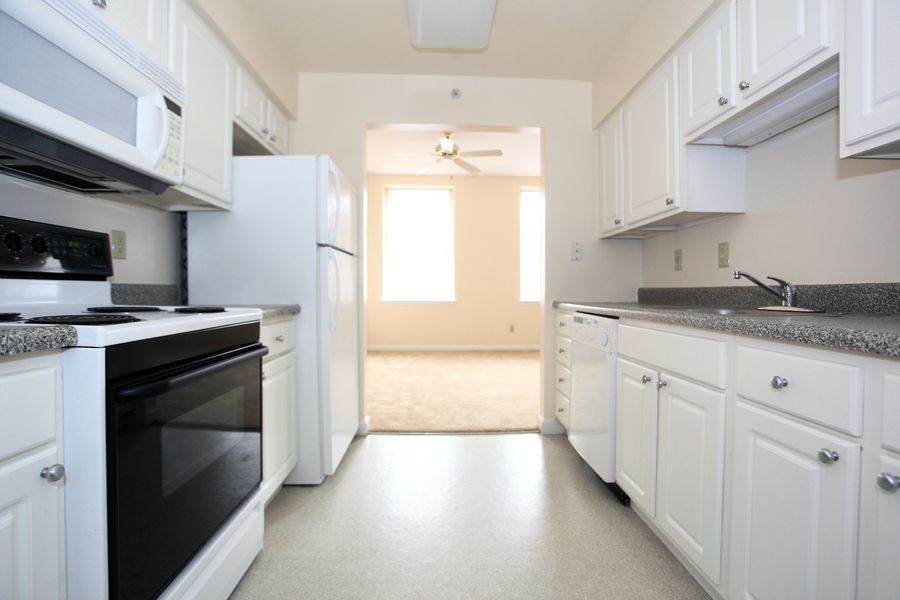 an empty kitchen with white cabinets and black appliances