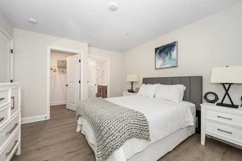 A bedroom with a large bed and a painting on the wall.