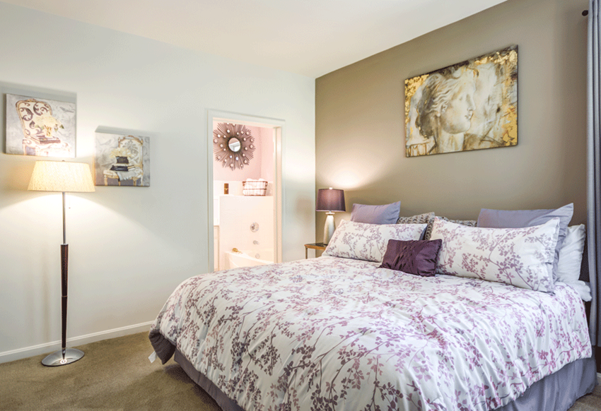 a bedroom with a bed and a painting on the wall