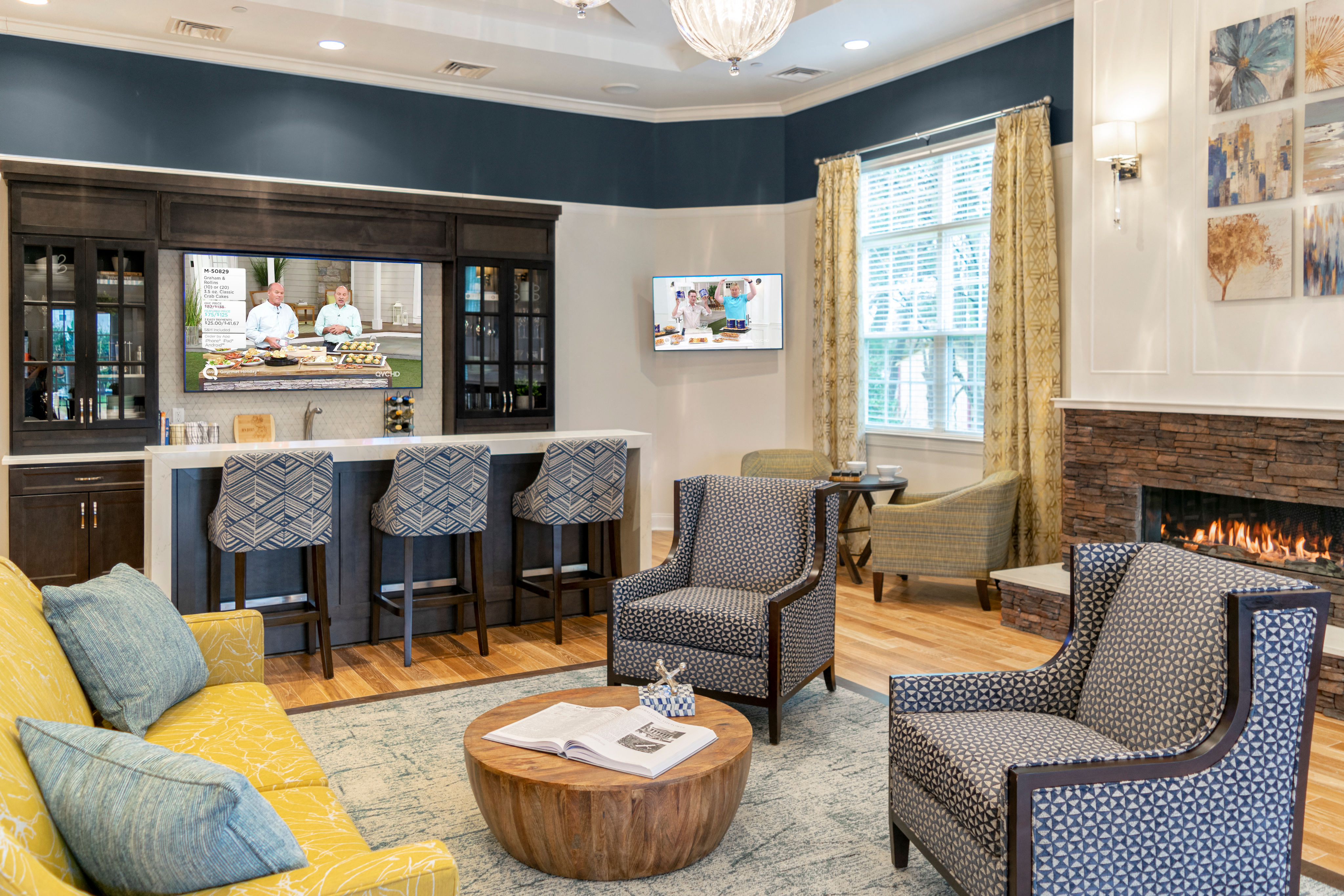 a living room with a fireplace and a bar with chairs