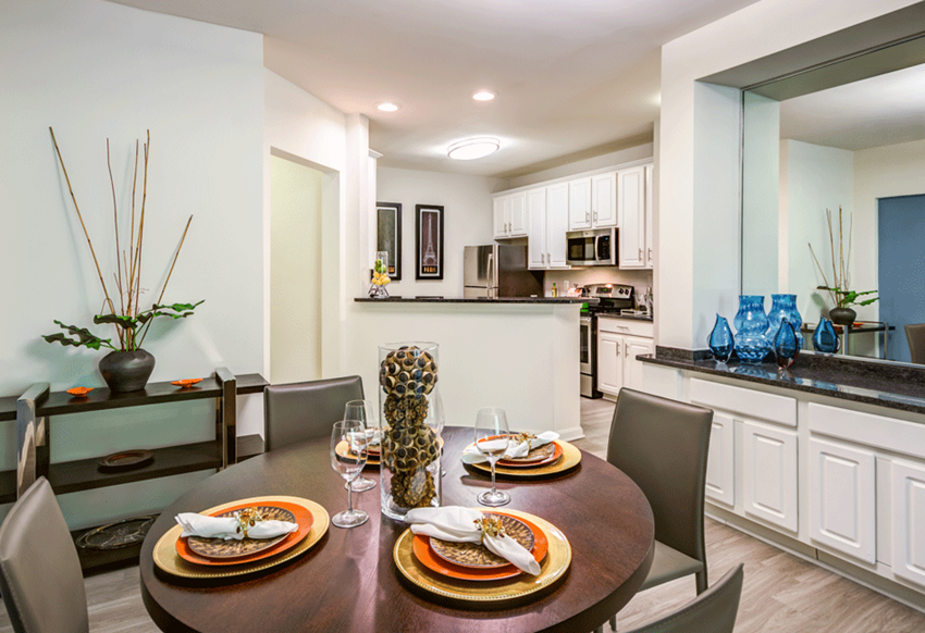 a dining room table with plates of food and a kitchen in the background