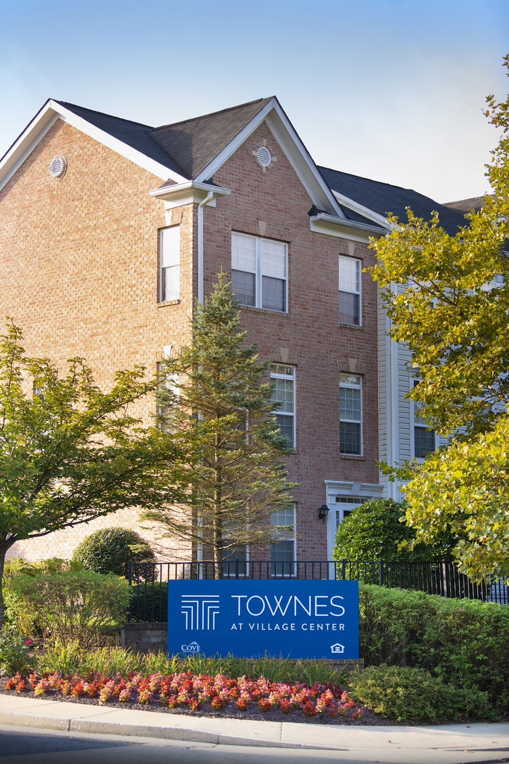 a building with a blue sign in front of it at Townes at Village Center Apartments, Reisterstown, Maryland