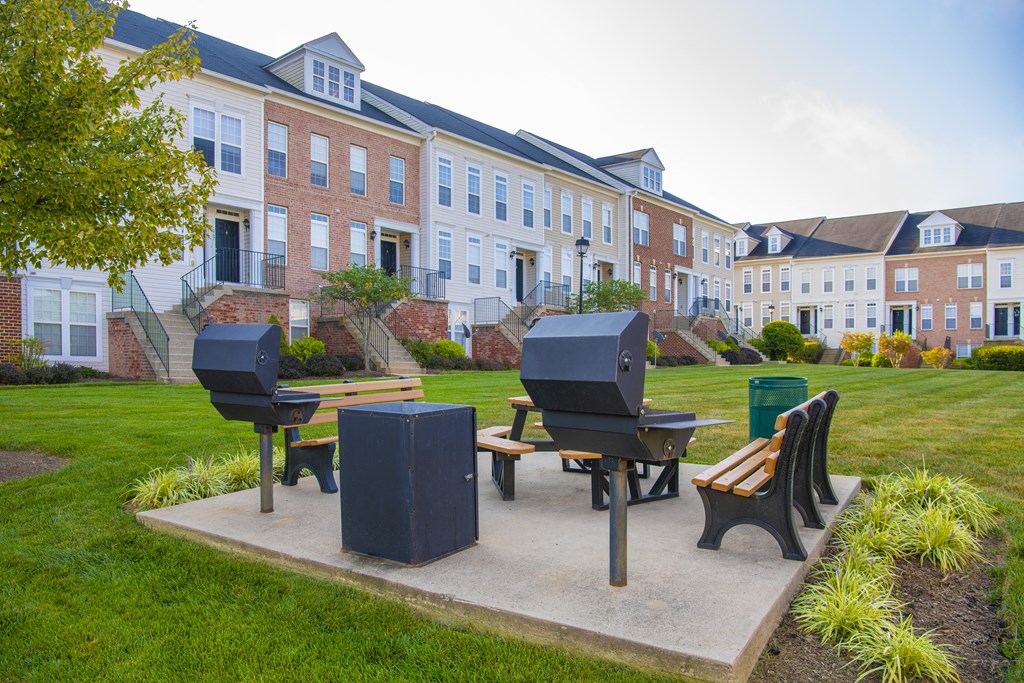 a park with a picnic table and benches in front of a building at Townes at Village Center Apartments, Reisterstown, MD, 21136