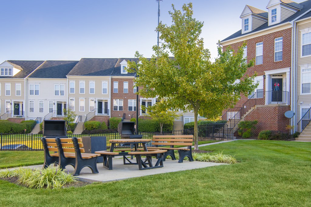 a patio with benches and a table in front of a building at Townes at Village Center Apartments, Maryland, 21136