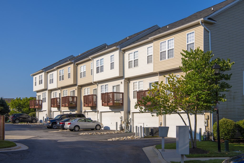 an apartment building with cars parked in front of it at Townes at Village Center Apartments, Reisterstown, 21136
