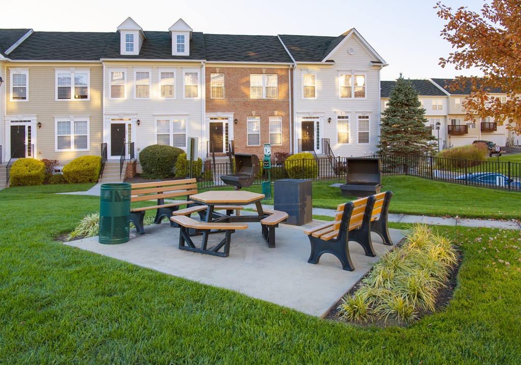 a picnic area with benches in front of an apartment building at Townes at Village Center Apartments, Reisterstown