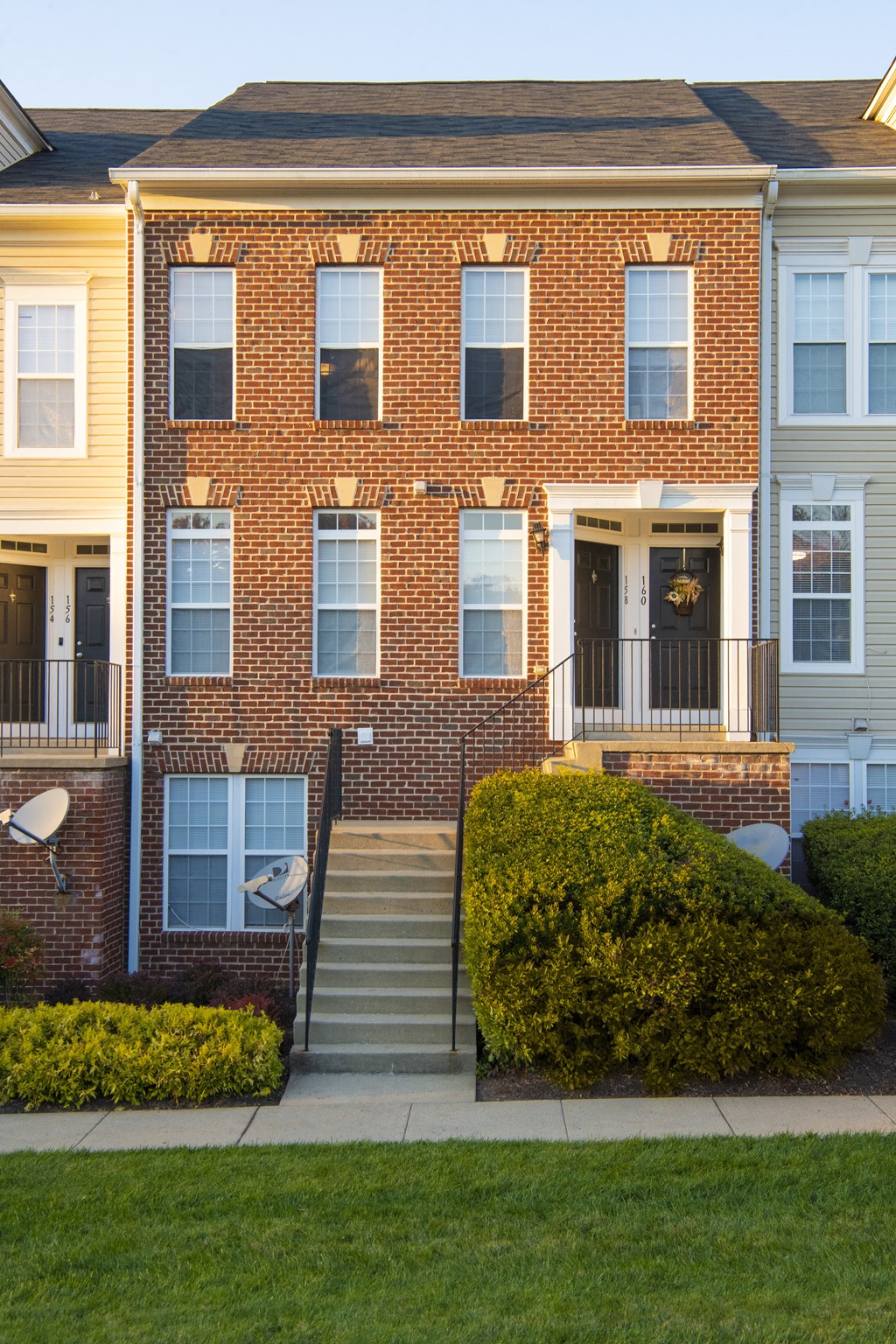 the front of a brick apartment building with stairs and a lawn at Townes at Village Center Apartments, Reisterstown, 21136