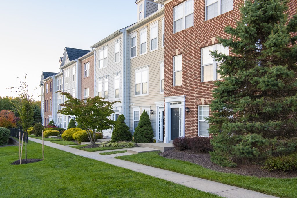 Building exterior with garden and trees at Townes at Village Center Apartments, Maryland, 21136