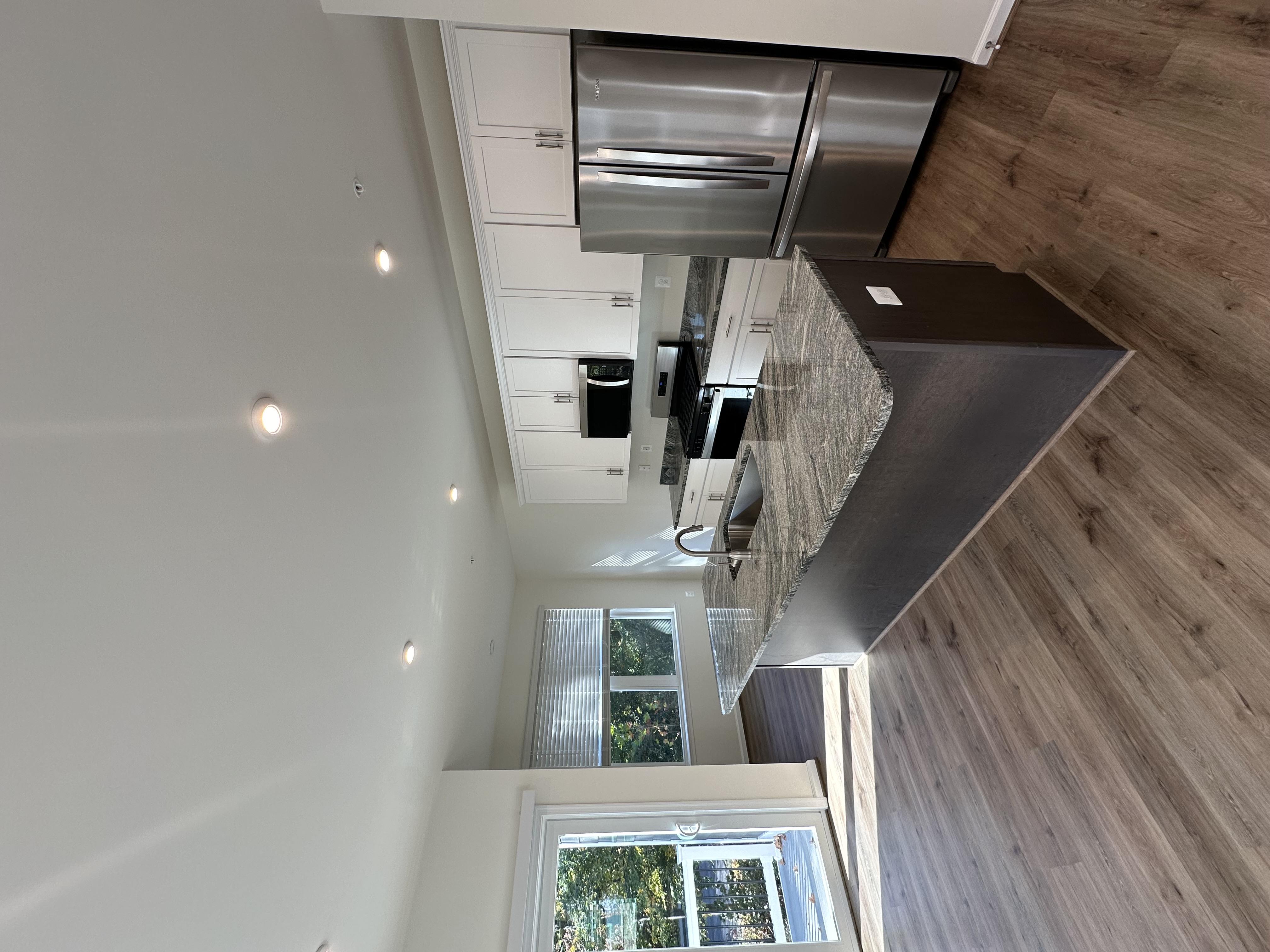 A modern kitchen with a stainless steel refrigerator and wooden ceiling.