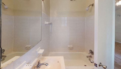 A white bathroom with a tub and shower at Prince Georgetown Apartments, Riverdale