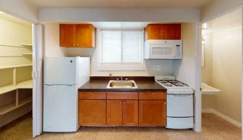 A kitchen with white appliances and wooden cabinets at Prince Georgetown Apartments, Riverdale