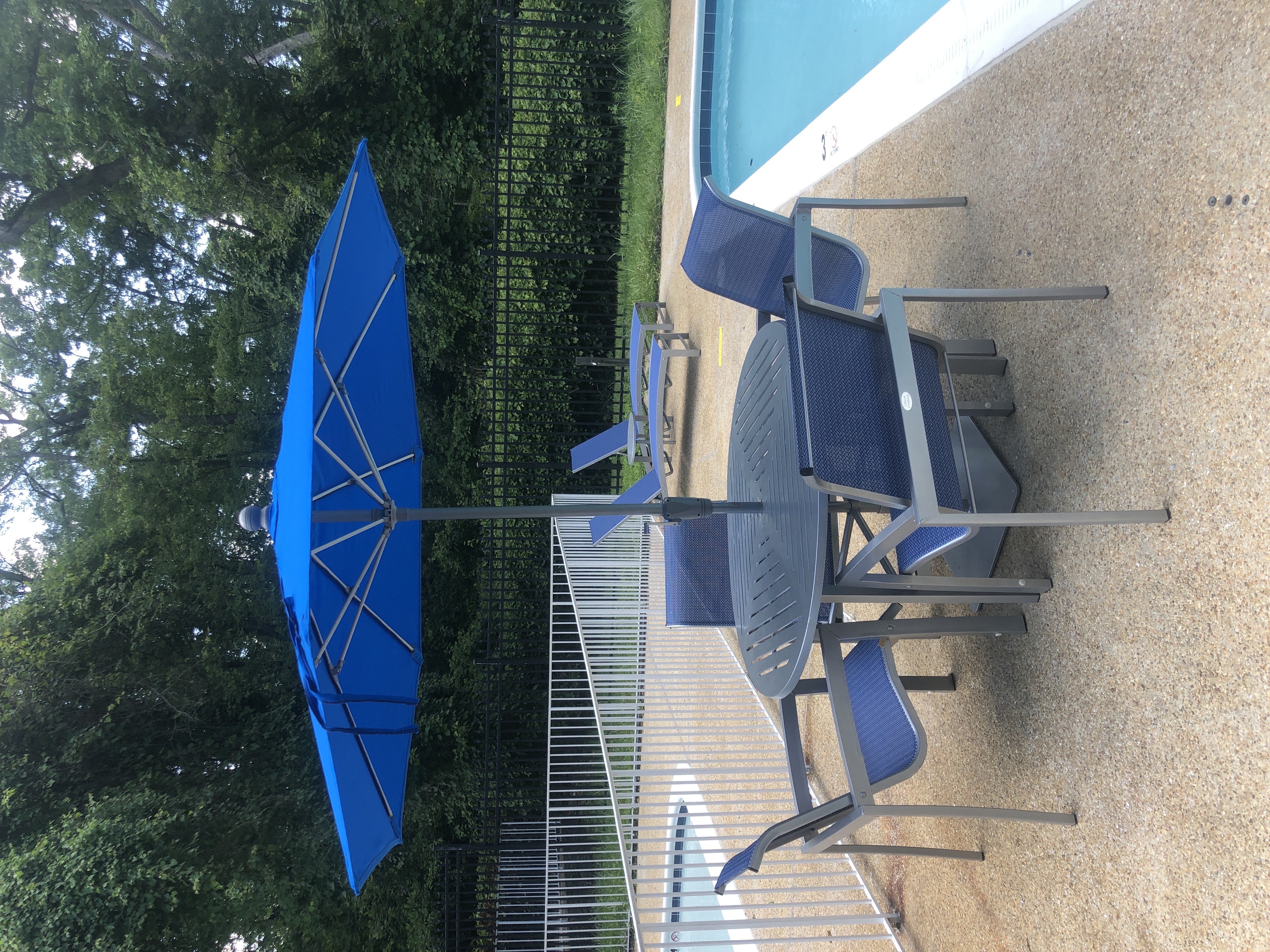 A blue umbrella is next to a pool.