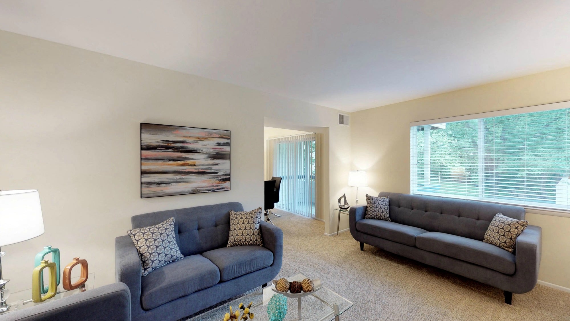 A living room with two grey couches and a painting on the wall.