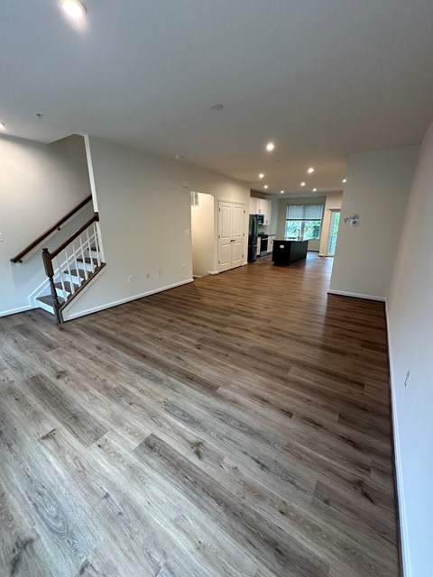 A spacious room with wooden flooring and a staircase.