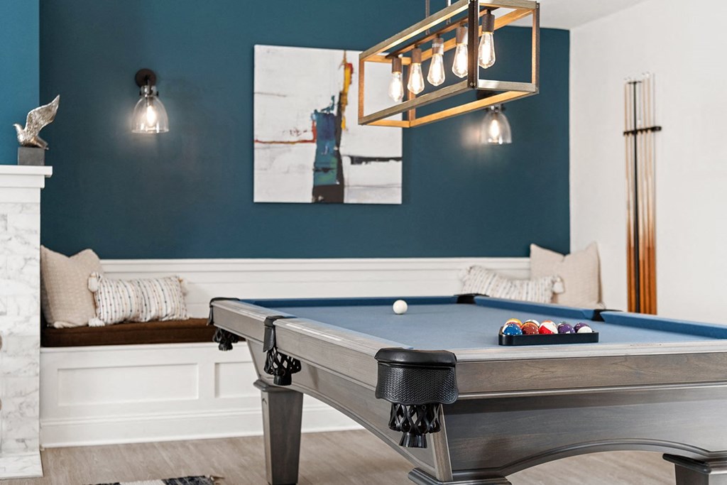 A pool table with a lighted billiard light above it. at Spa Cove Apartments, Annapolis, 21403