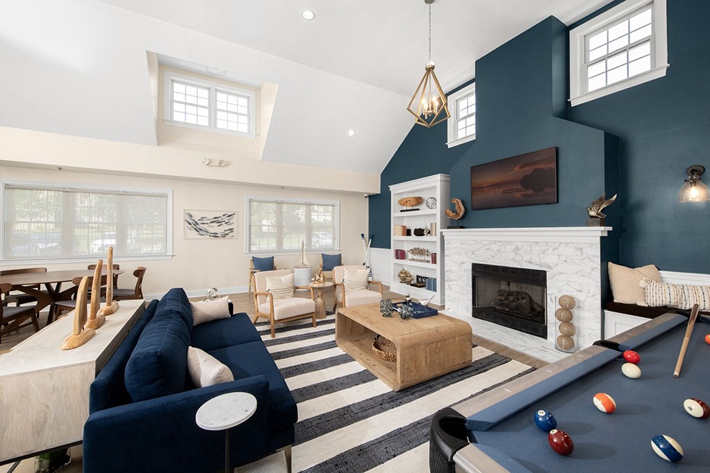 A blue sofa and a pool table are in a room with a fireplace. at Spa Cove Apartments, Annapolis, 21403