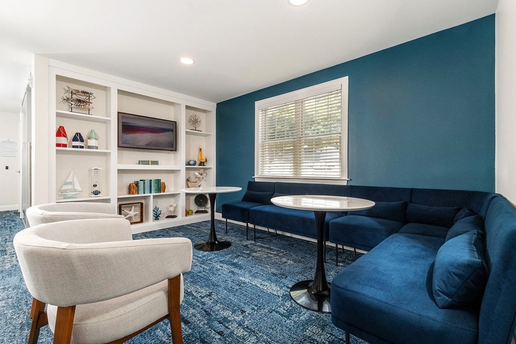 A blue sofa sits in a living room with a white chair and a small table. at Spa Cove Apartments, Annapolis, 21403