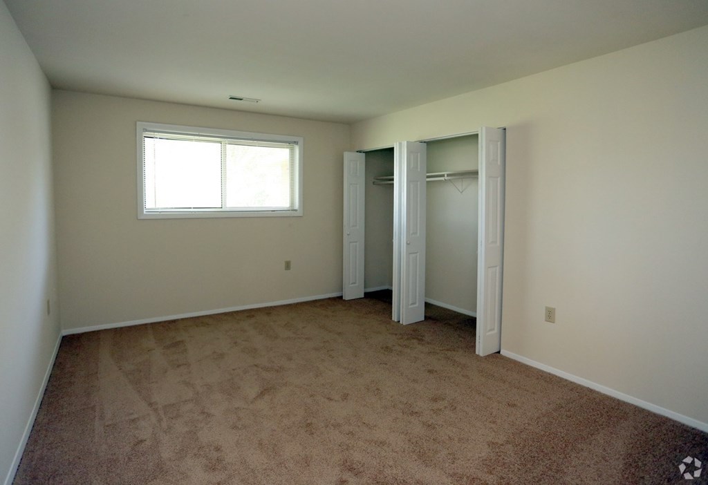 A room with a carpeted floor, a window, and a closet with a door. at Spa Cove Apartments, Annapolis, 21403
