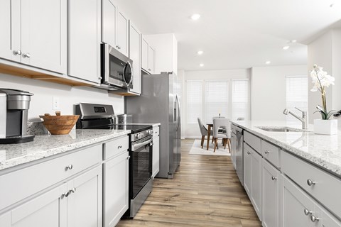 A modern kitchen with white cabinets and stainless steel appliances.