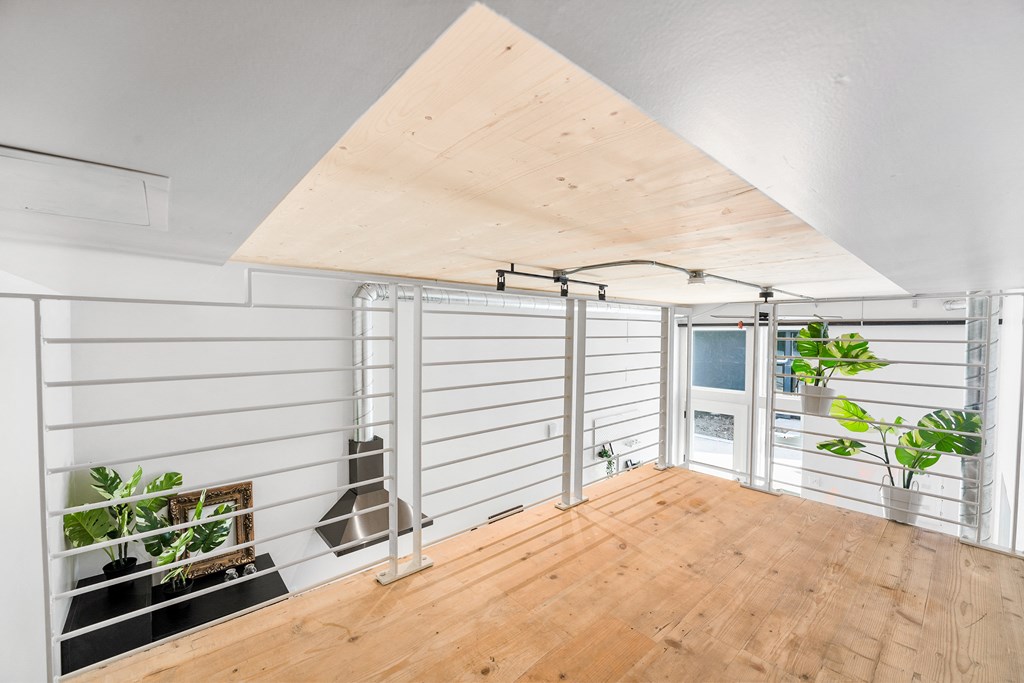 a living room with white walls and a wooden floor and a sliding glass door