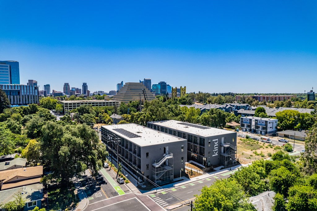 an aerial view of three buildings and a city skyline