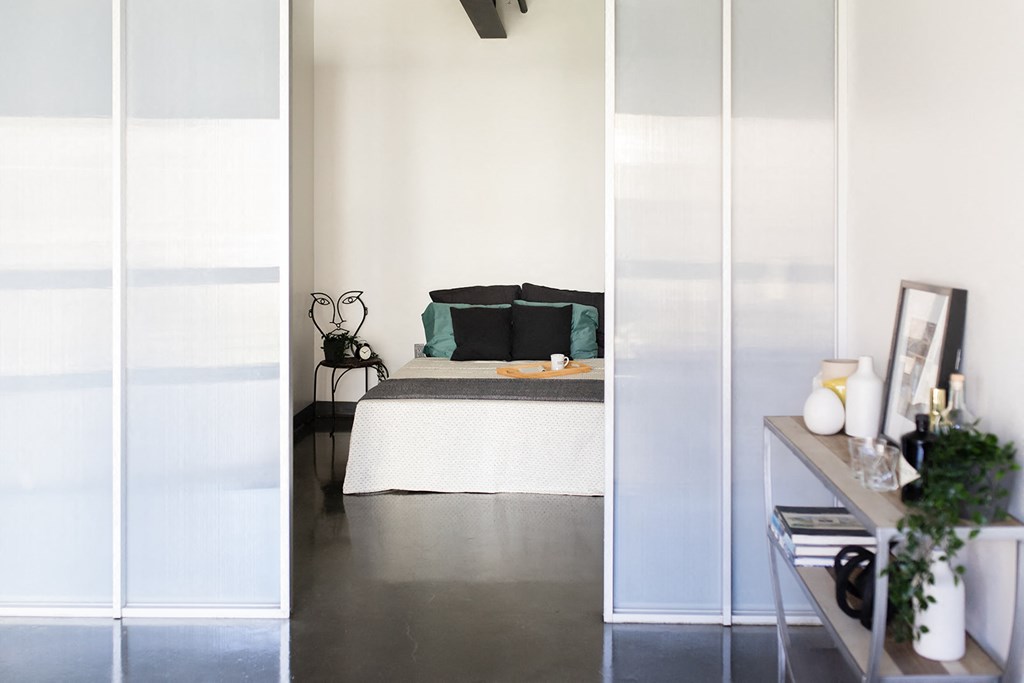 a bedroom with white walls and a bed with green pillows