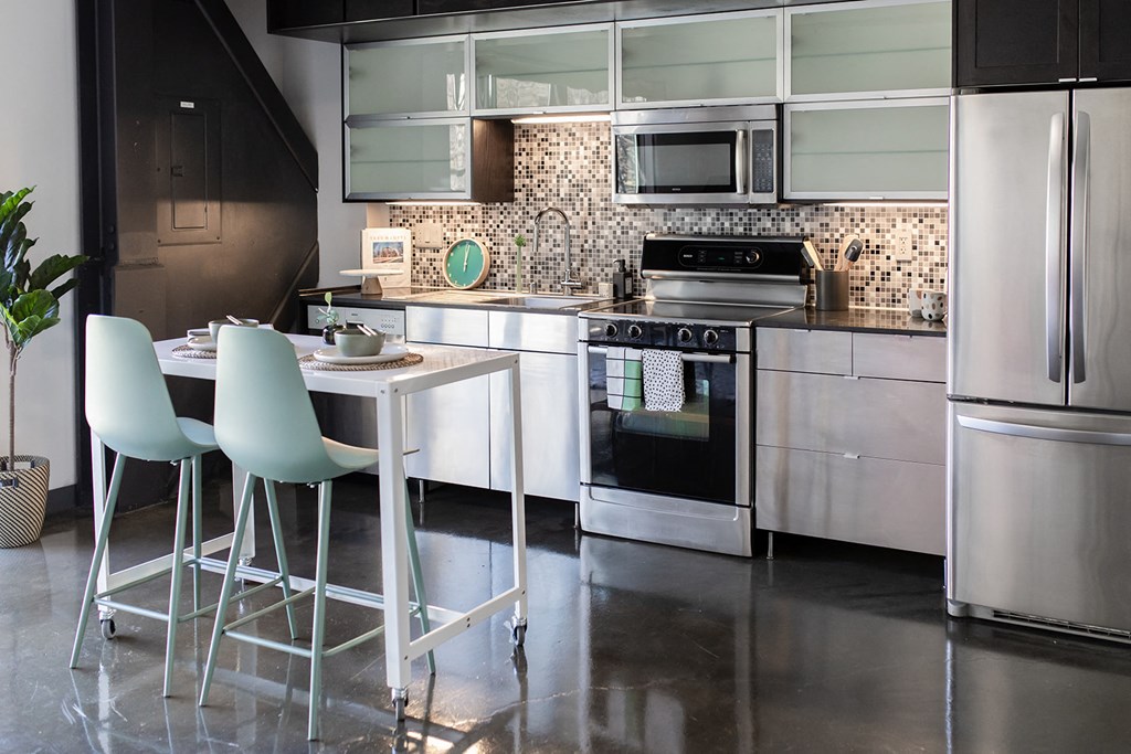 a kitchen with stainless steel appliances and a white table and chairs