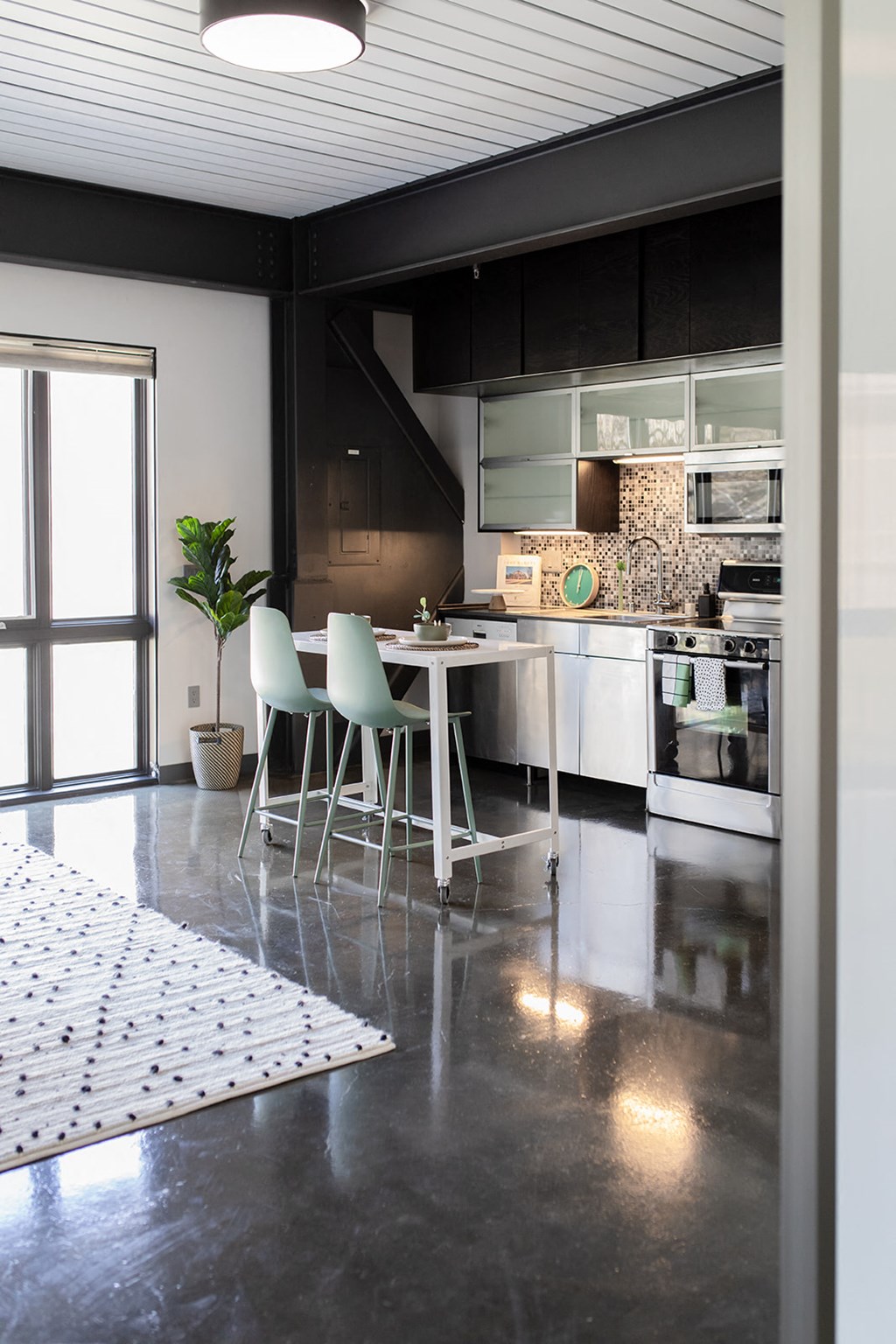 a kitchen with black cabinets and a white rug