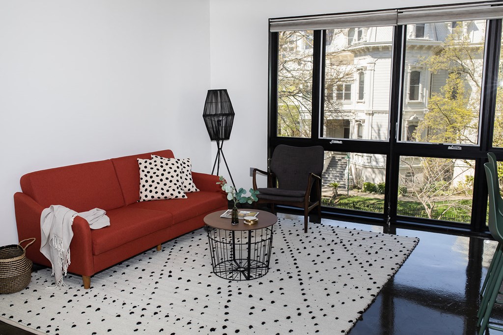 a living room with a red couch and a black and white rug